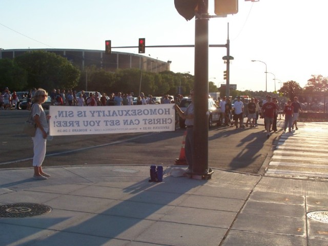 Crowd passing by banner, which reads, "Homosexuality is sin, Christ can set you free."